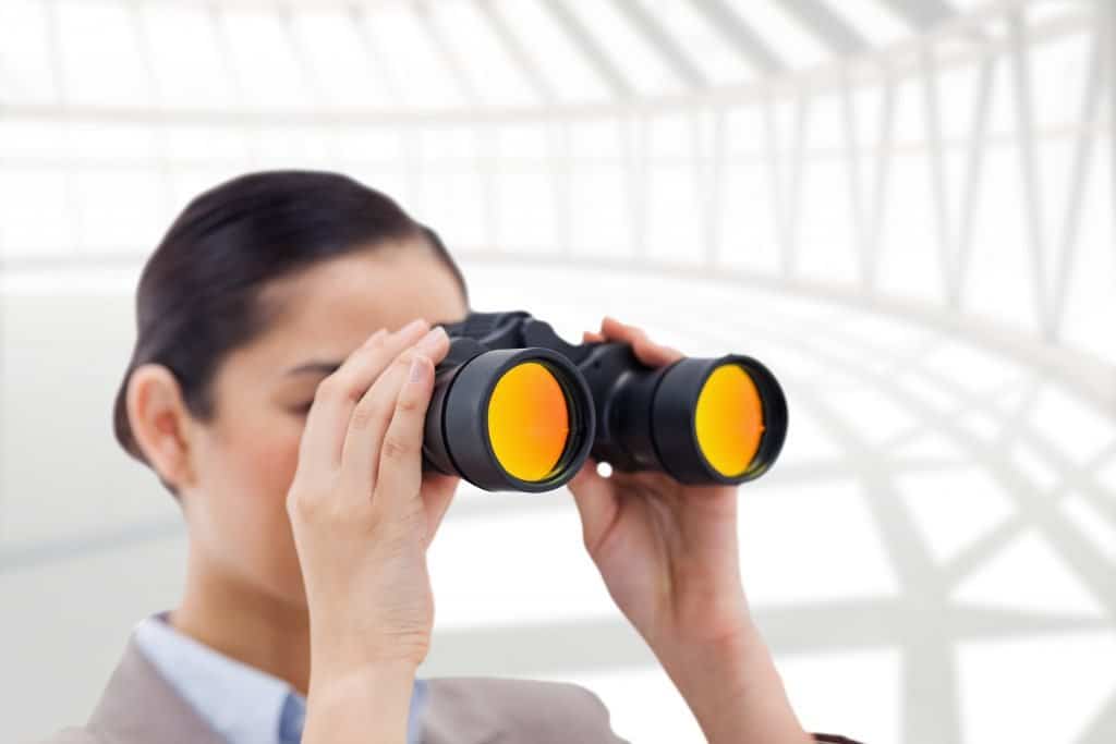A women entrepreneur holding a binocular. Searching for Target Market
