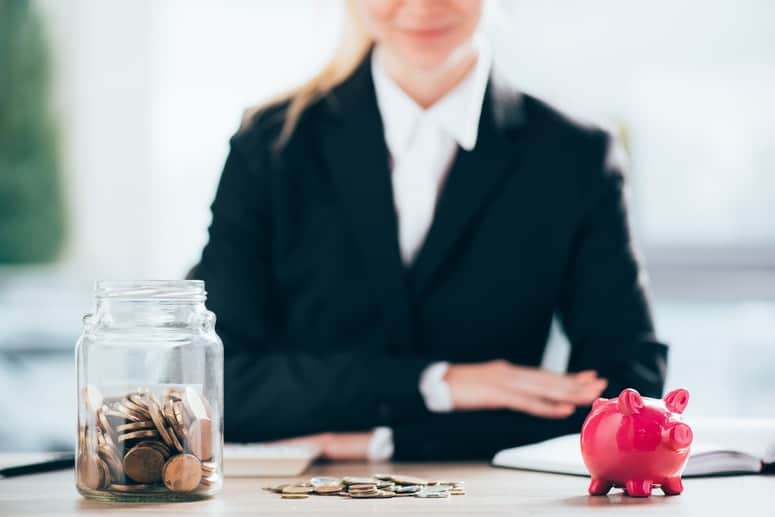 Businesswoman with piggy bank and jar of coins