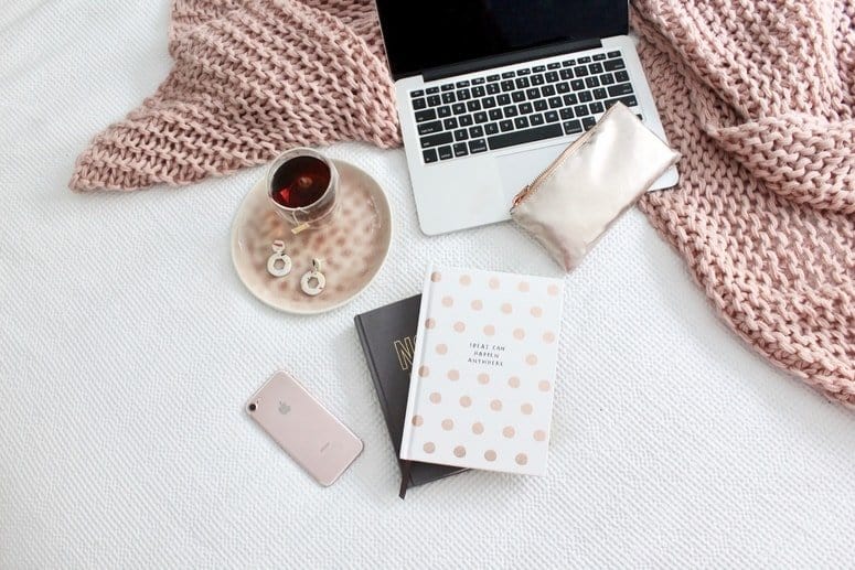 A laptop, notebook and coffee under the bed.