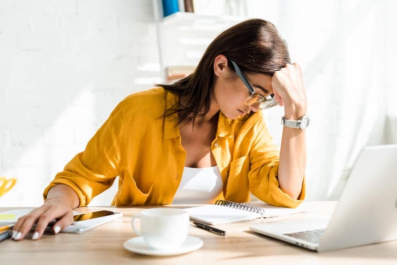 A women entrepreneur sitting on her working table, thinking, looking a stress and overwhelmed.
