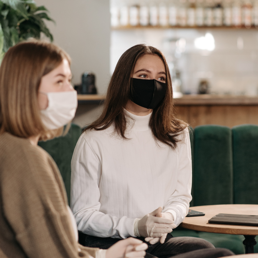 Two woman wearing face masks inside the meeting room.